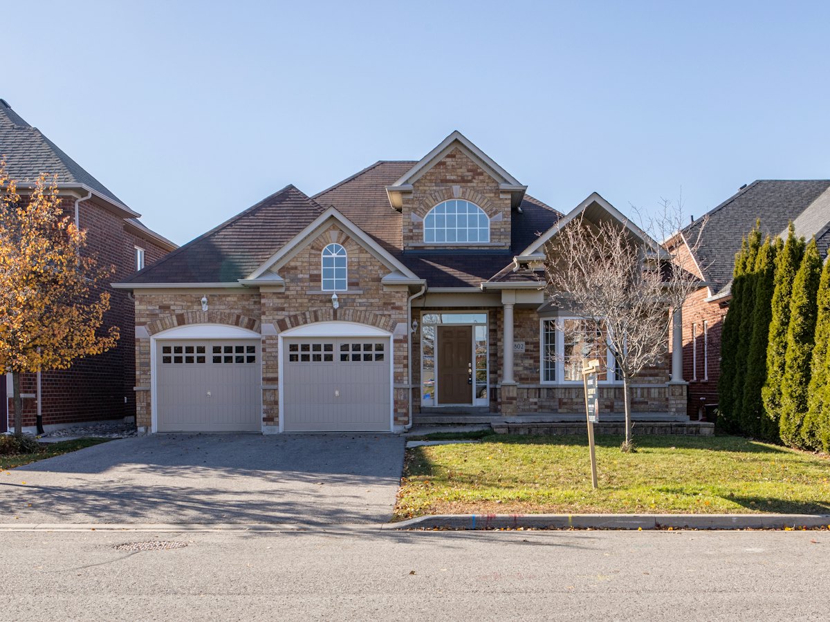 Brick two storey home on a tree lined street in autumn